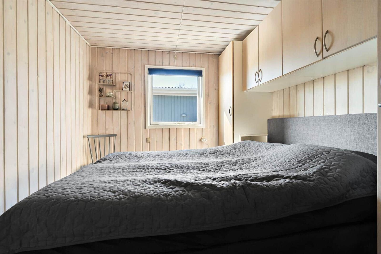 Schlafzimmer mit Bett, Fenster und Schränken an den Wänden.