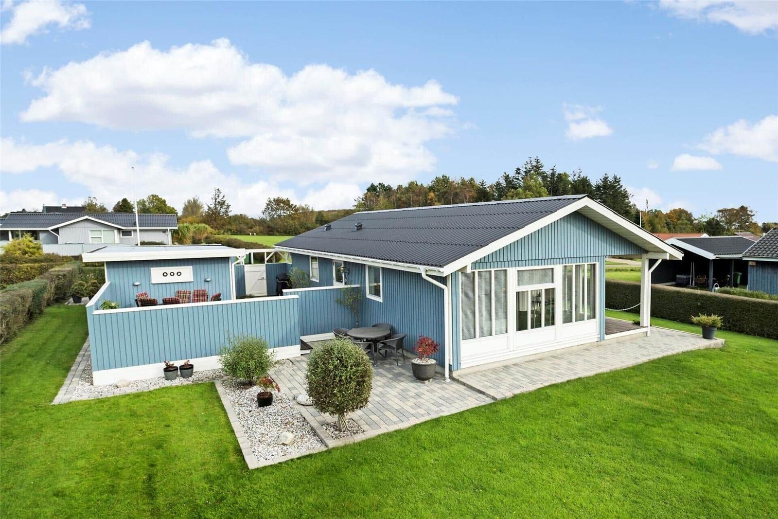 Blauer Ferienhaus mit Terrasse und Garten unter blauem Himmel.