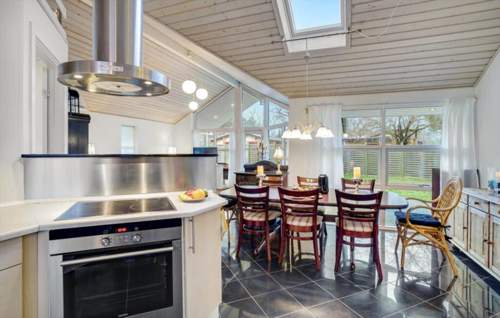 Kitchen with dining area, black tiles, wooden ceiling, and large window.