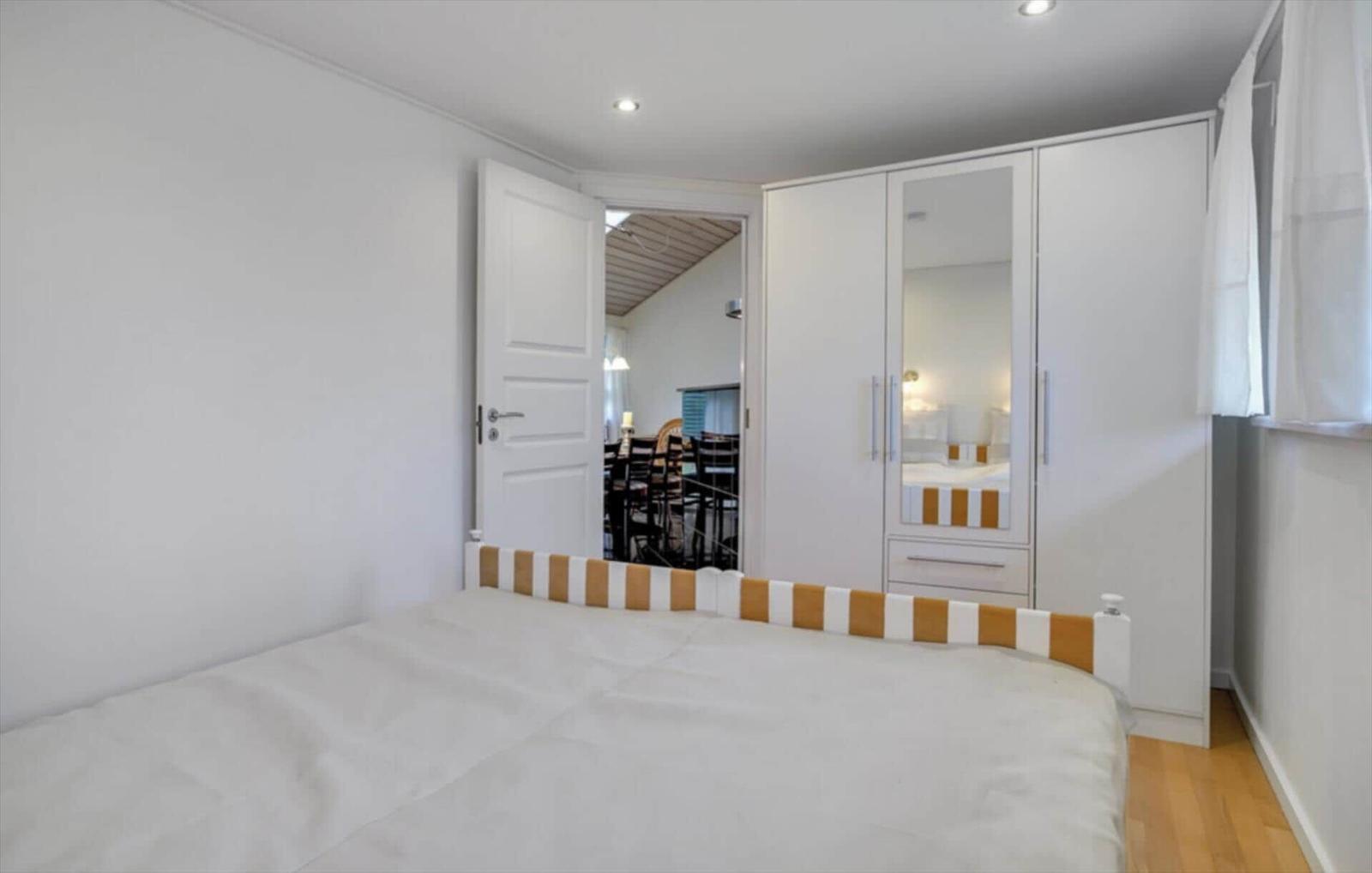 Bedroom with bed, wardrobe, and door to dining area.