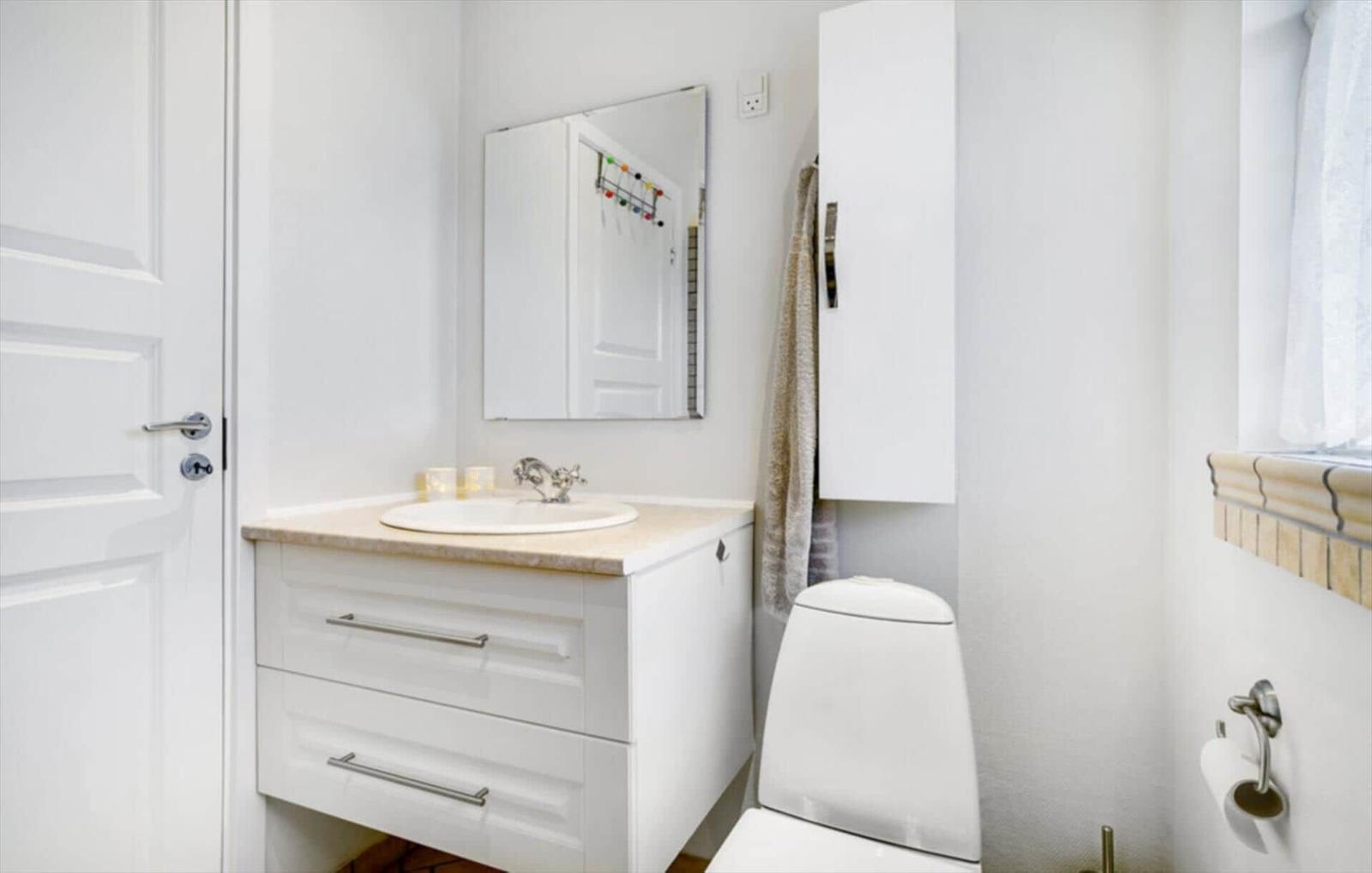 Bathroom with sink, mirror, toilet, and window