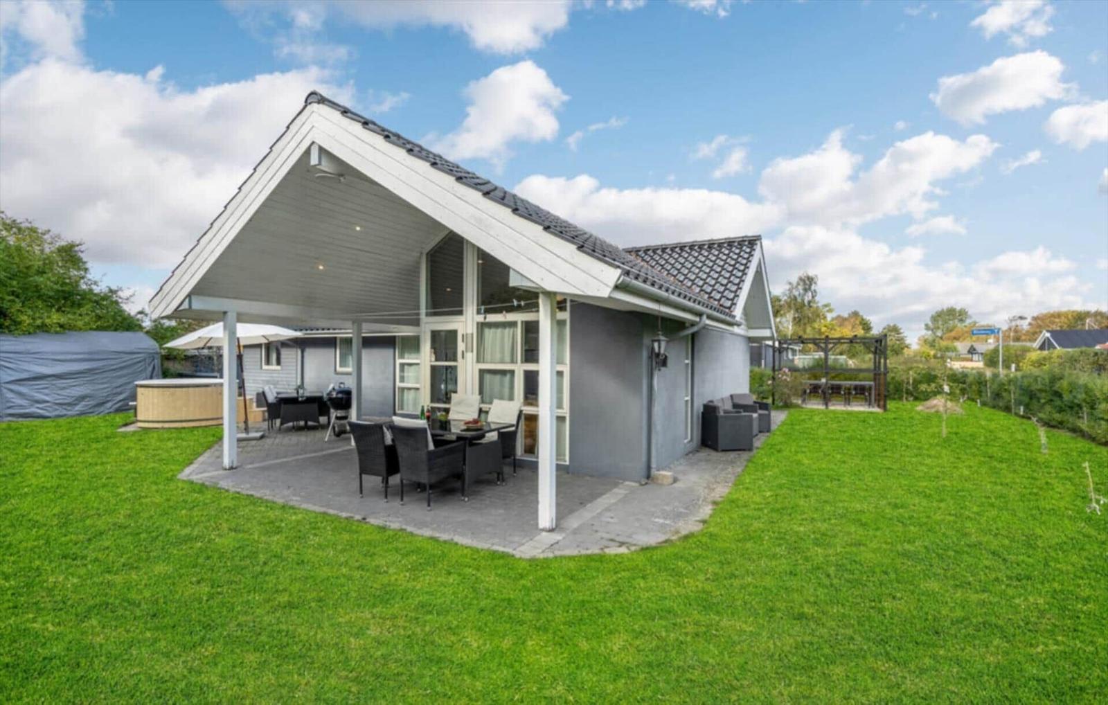 A house with terrace, garden, and outdoor seating under a blue sky.