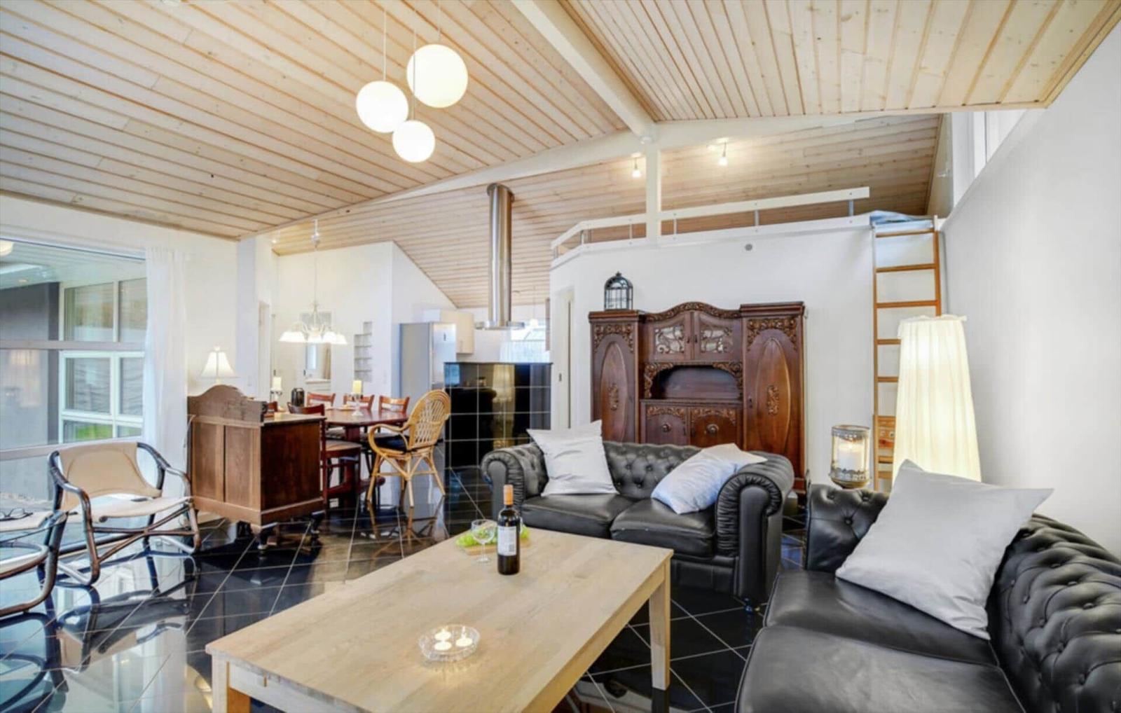 Living and dining area with wooden ceiling, leather sofa, and wooden table.