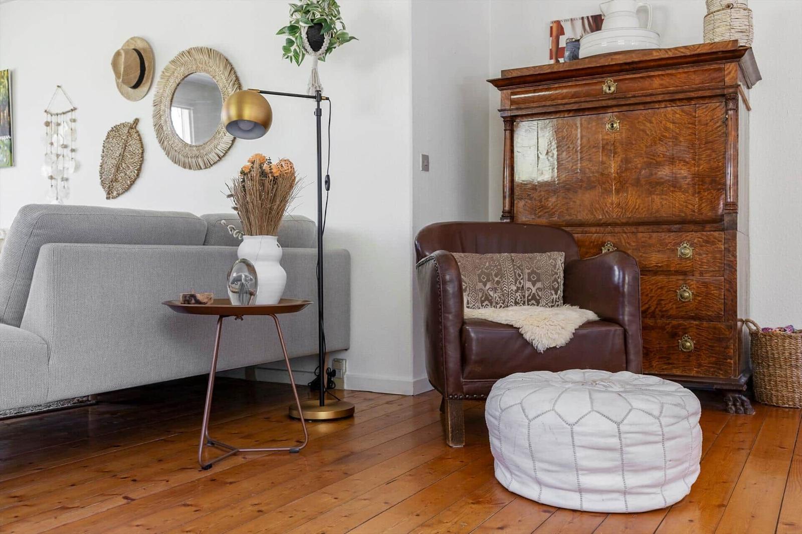 Living room with gray sofa, brown leather armchair, and wooden floor.