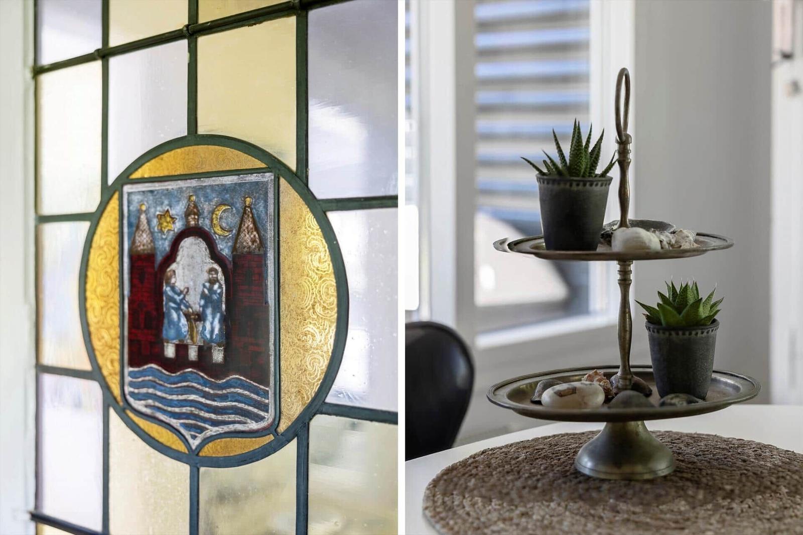 Stained glass window with coat of arms and two-tiered serving tray with succulents.