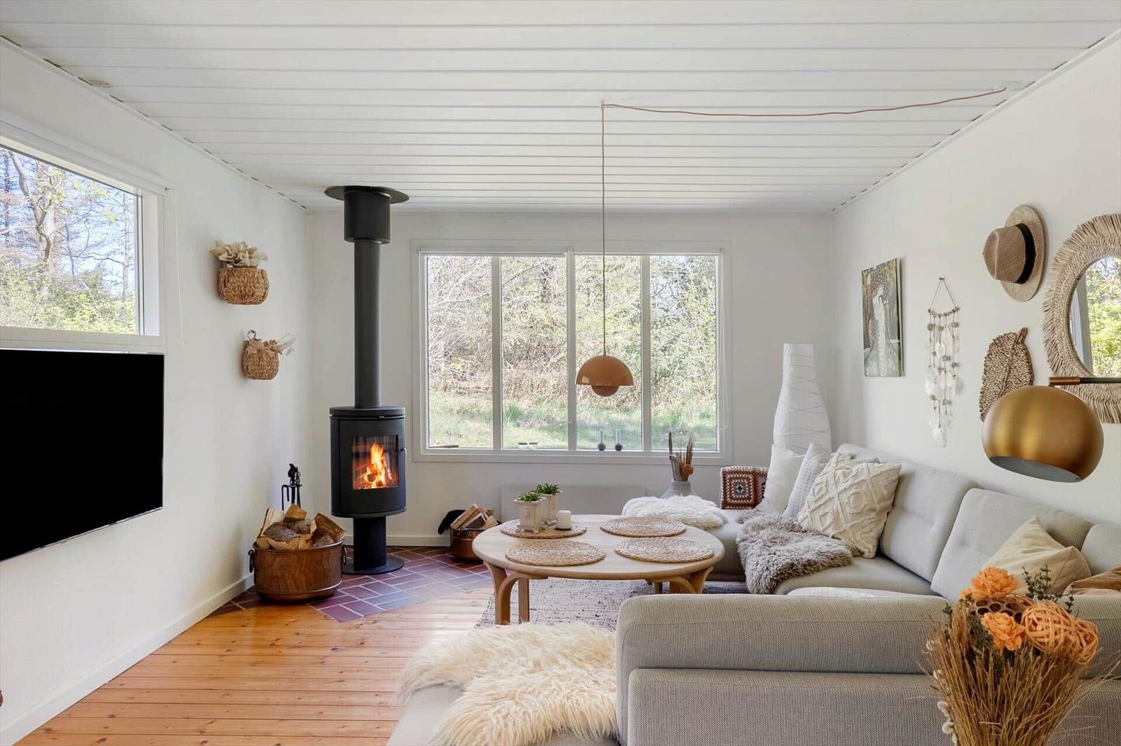Living room with fireplace, sofa, and hardwood floor. Large windows and wall decor.