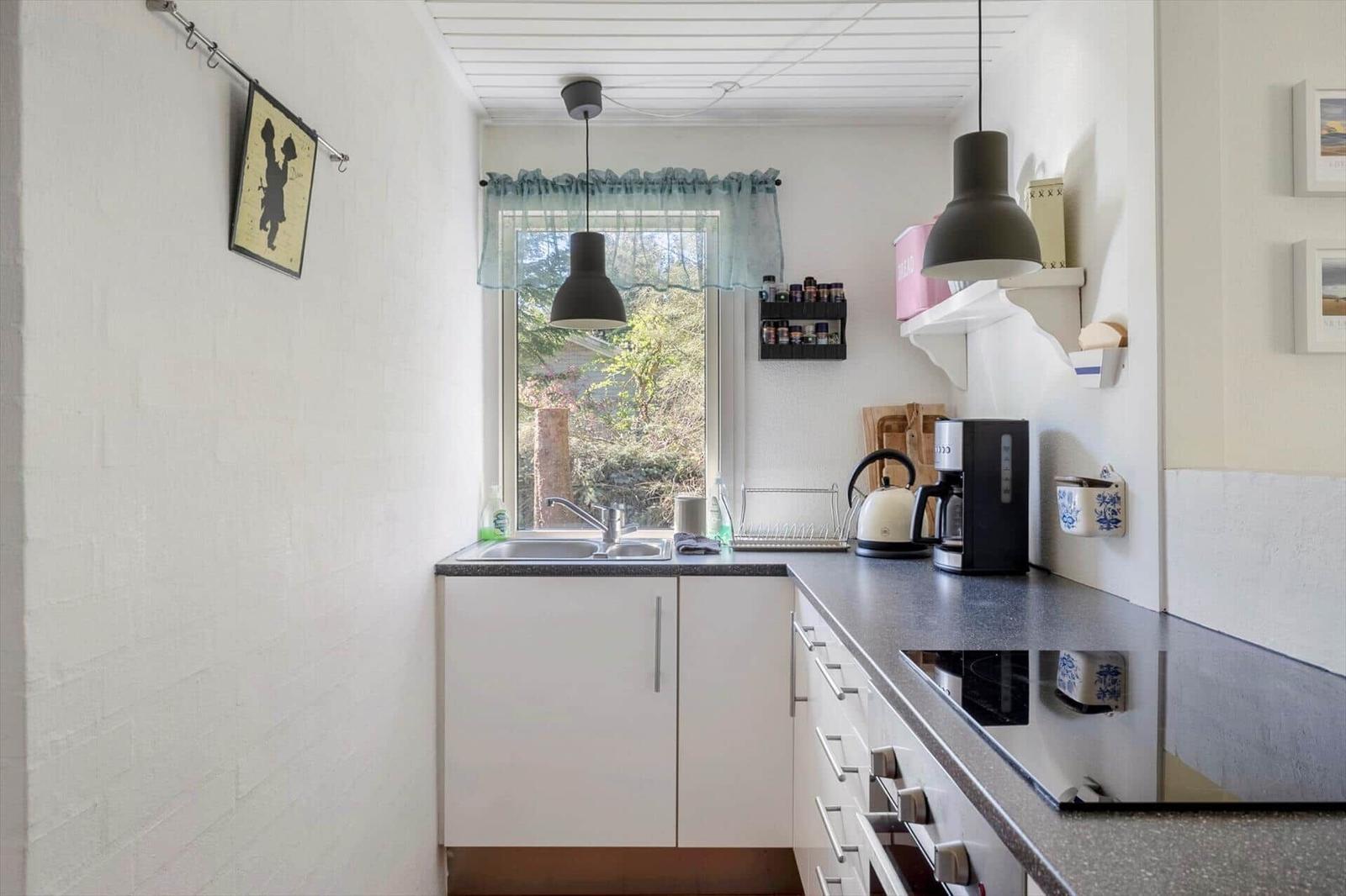 Kitchen with white cabinets, dark countertop, and window with view outside.
