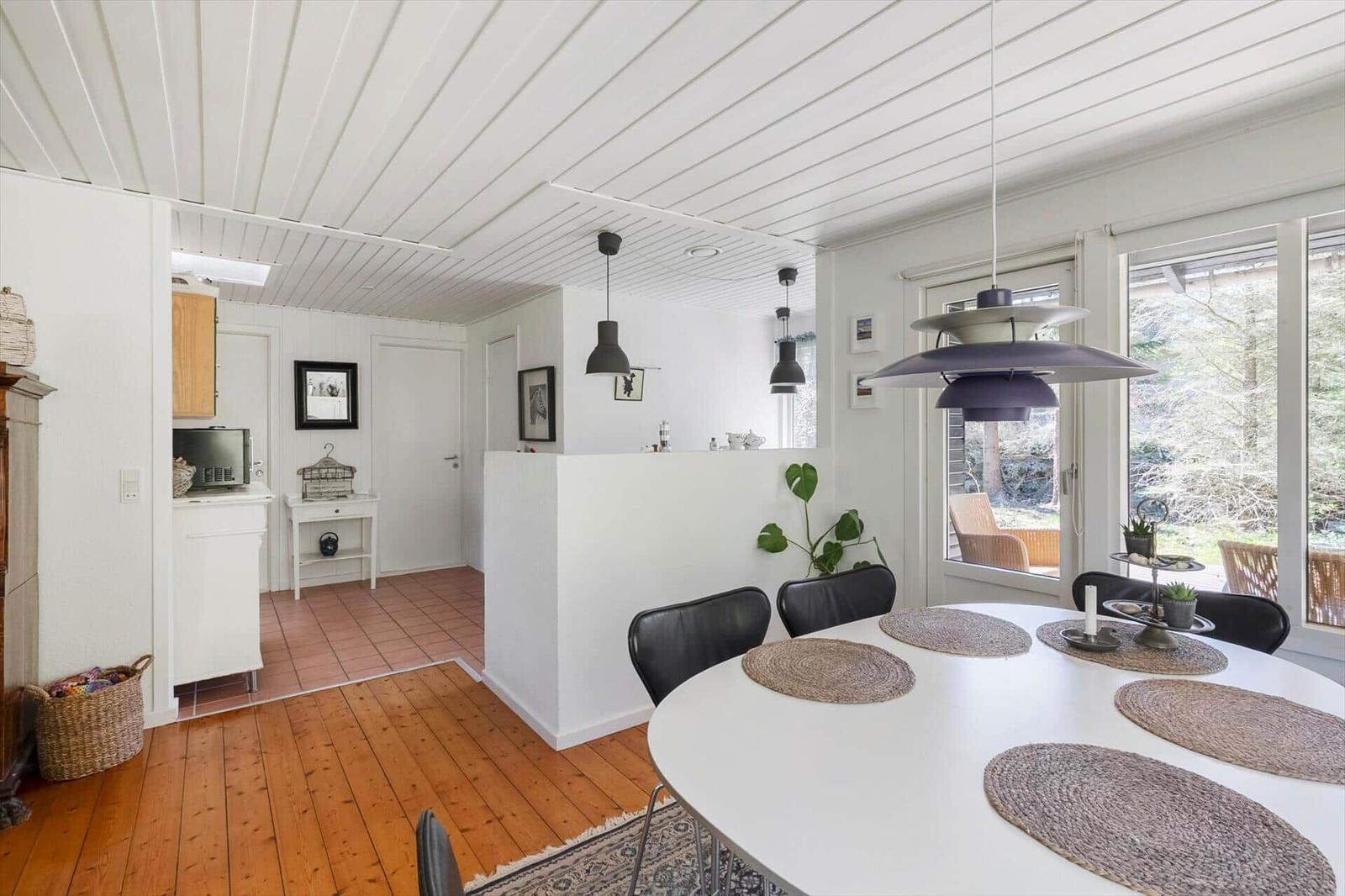 Dining area with round table and black chairs. Kitchen and living area are visible.