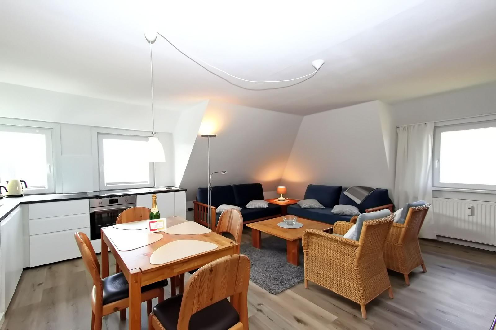 Wohn- und Essbereich mit Küchenzeile, Sofa und Esstisch mit Stühlen.