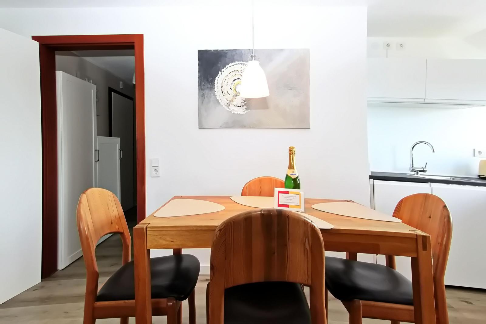 Esstisch mit vier Holzstühlen und Flasche Champagner
