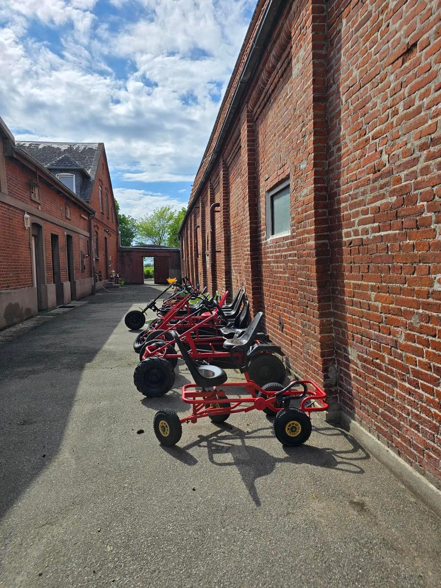 Rote Go-Karts stehen in einer Straße zwischen Backsteinhäusern.