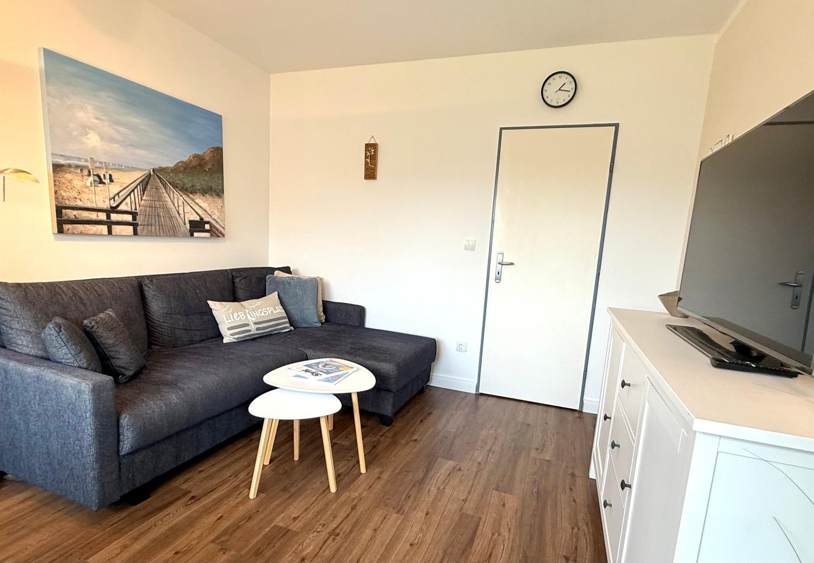 Wohnzimmer mit Sofa, Tisch, Fernseher und Wandbild