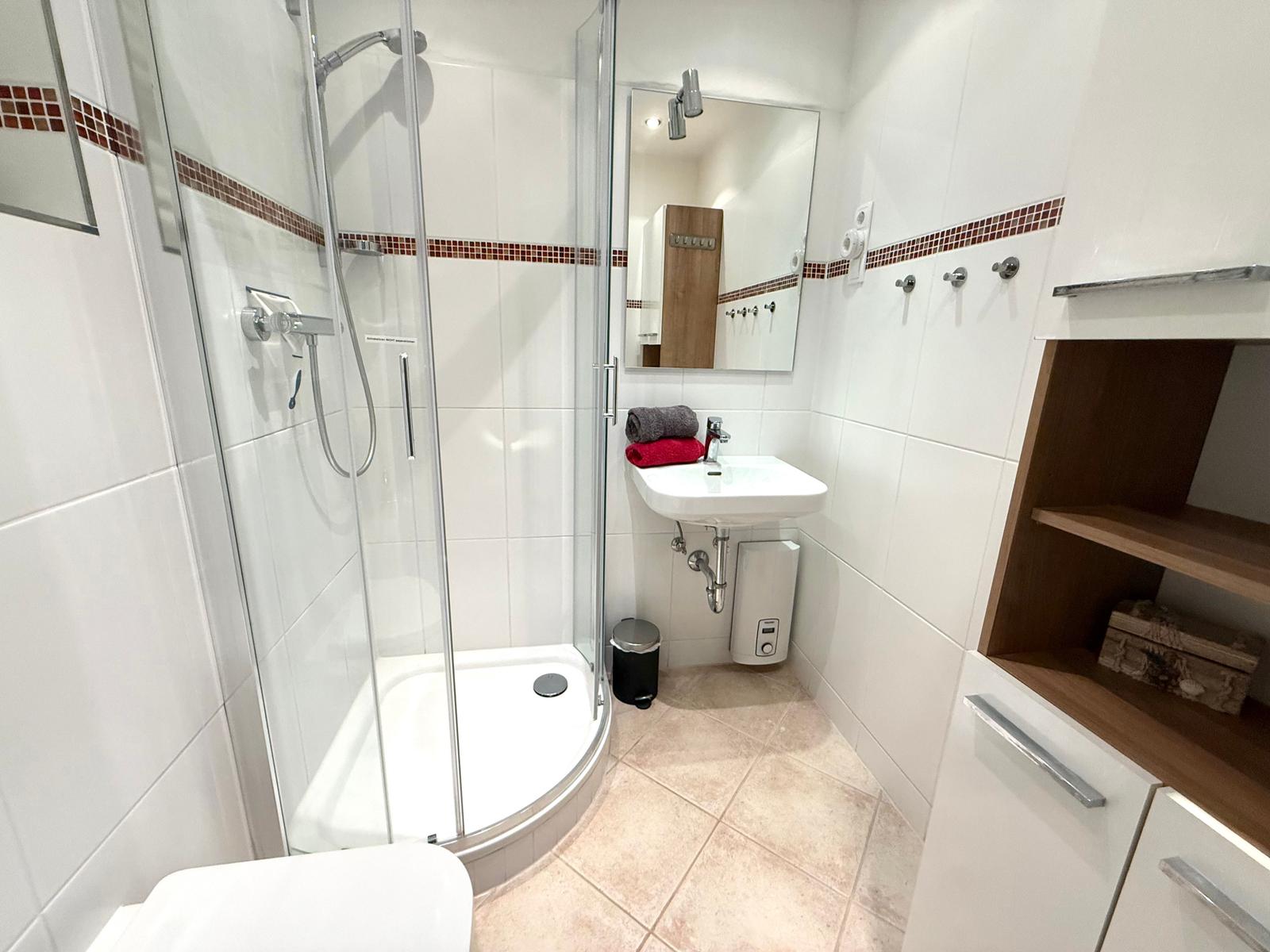 Helles Bad mit Runddusche, Handtuchheizkörper, Waschbecken und WC
