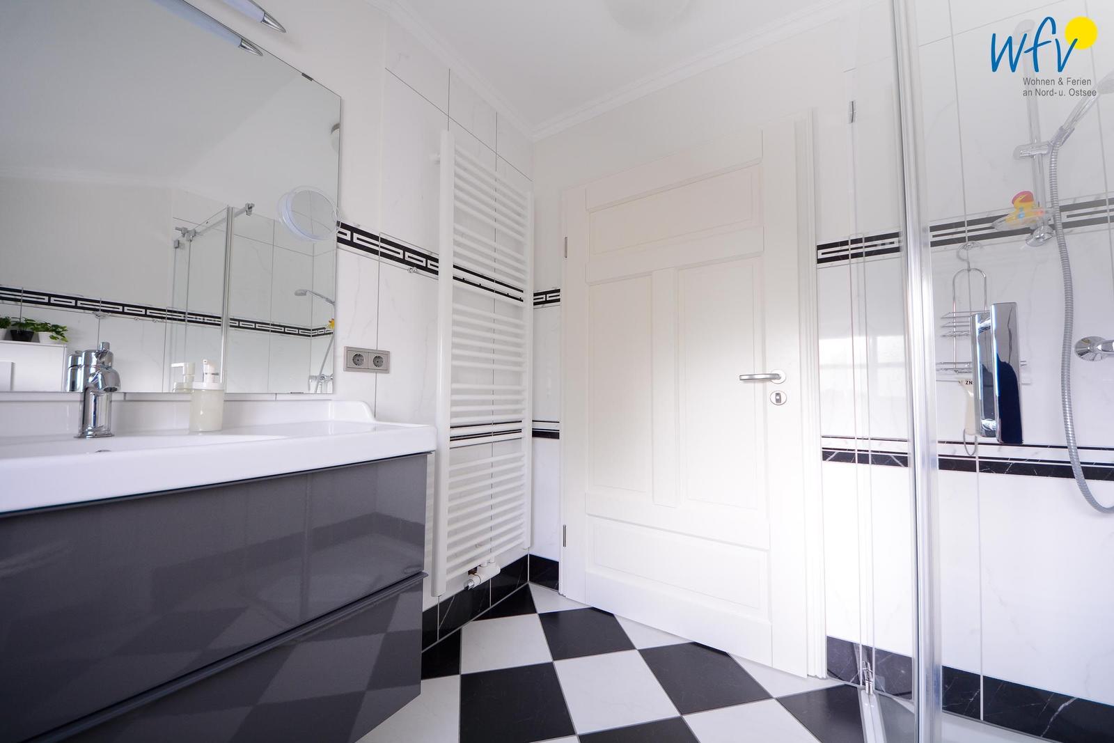 Badezimmer mit Dusche, Waschbecken und Heizkörper