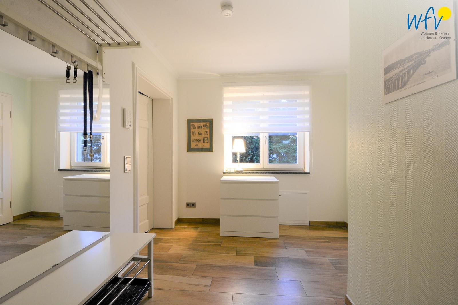Helle Wohnung mit Holzboden, Fenstern und weißen Schränken.