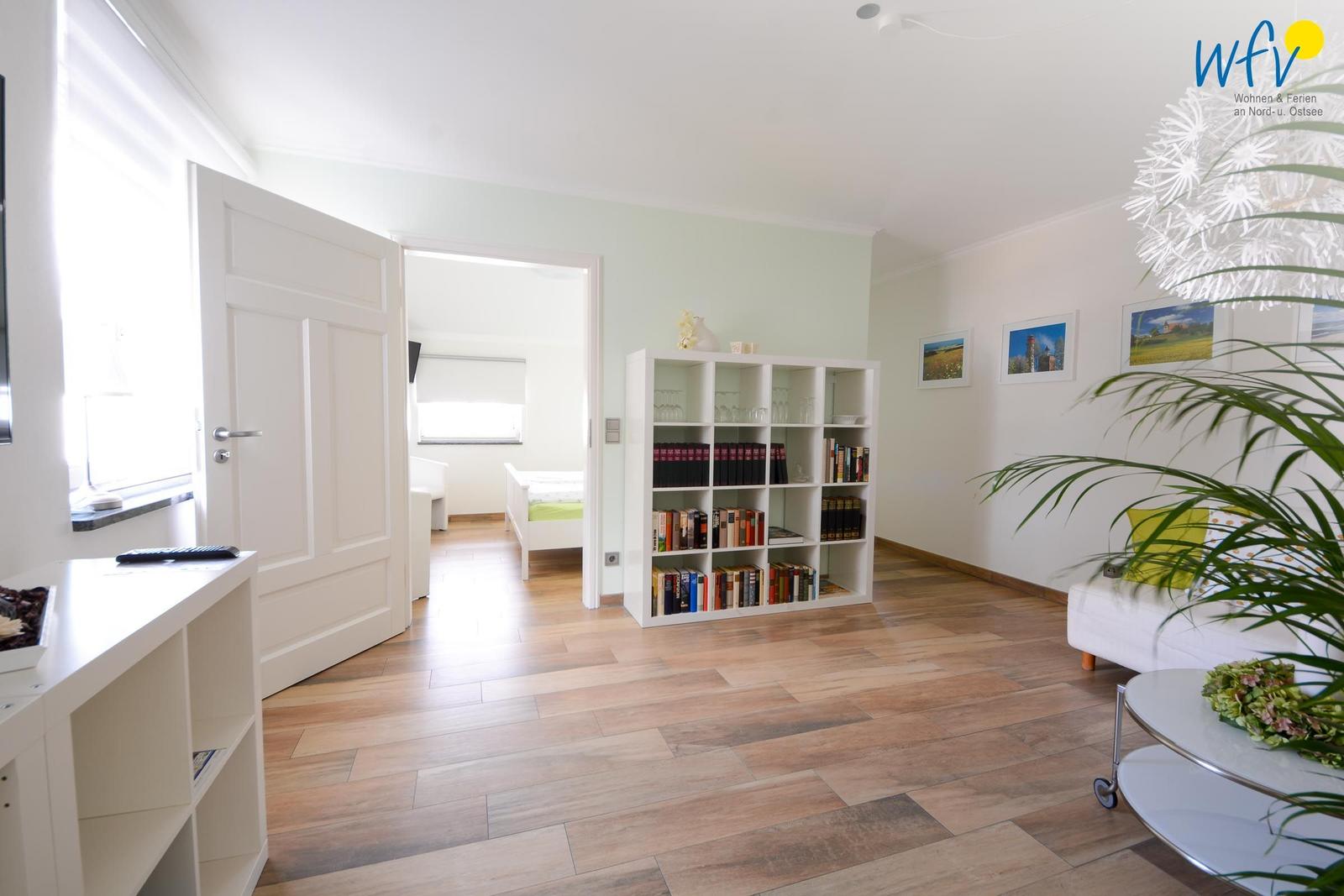 Wohnzimmer mit Bücherregal, Sofa und Blick in Schlafzimmer