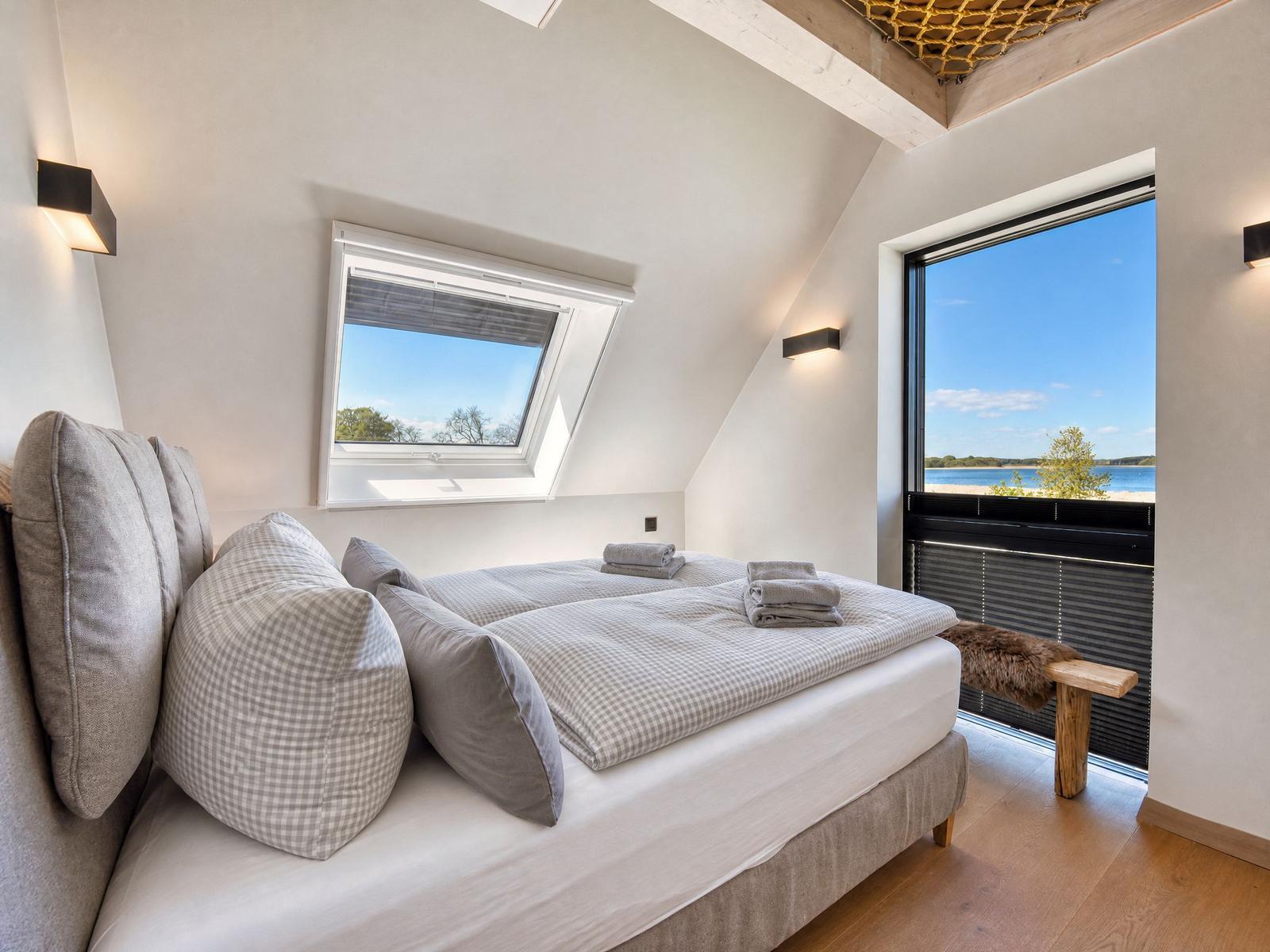 Bedroom with bed, windows, and view of water.