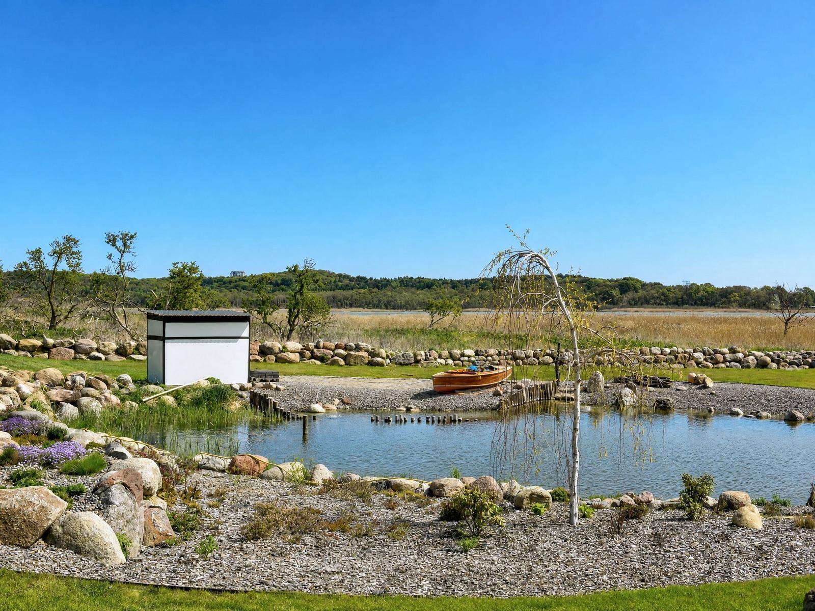 A small lake with a boat and a white shed in the background.