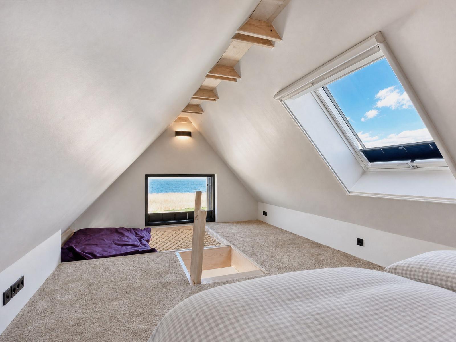 Attic room with sloped ceiling, skylight, and sea view.