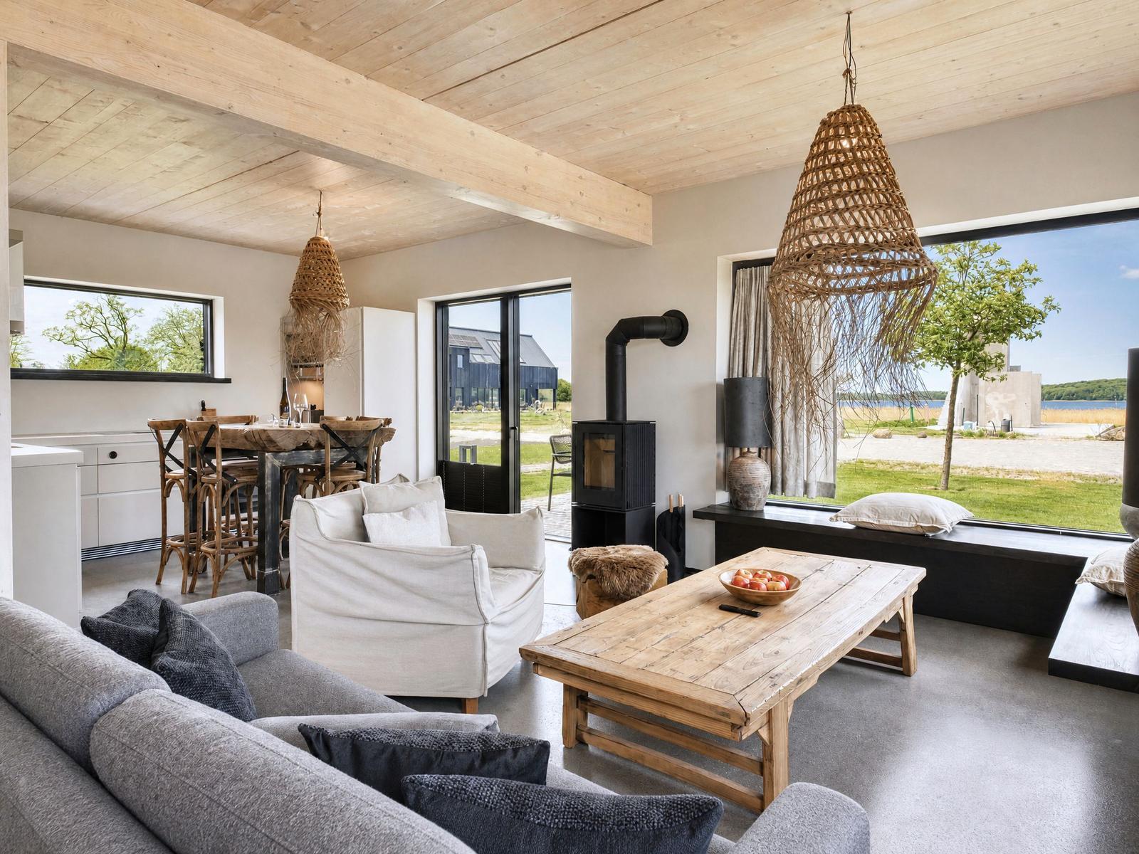 Living and dining area with wooden ceiling, sofa, table, and view of the lake.