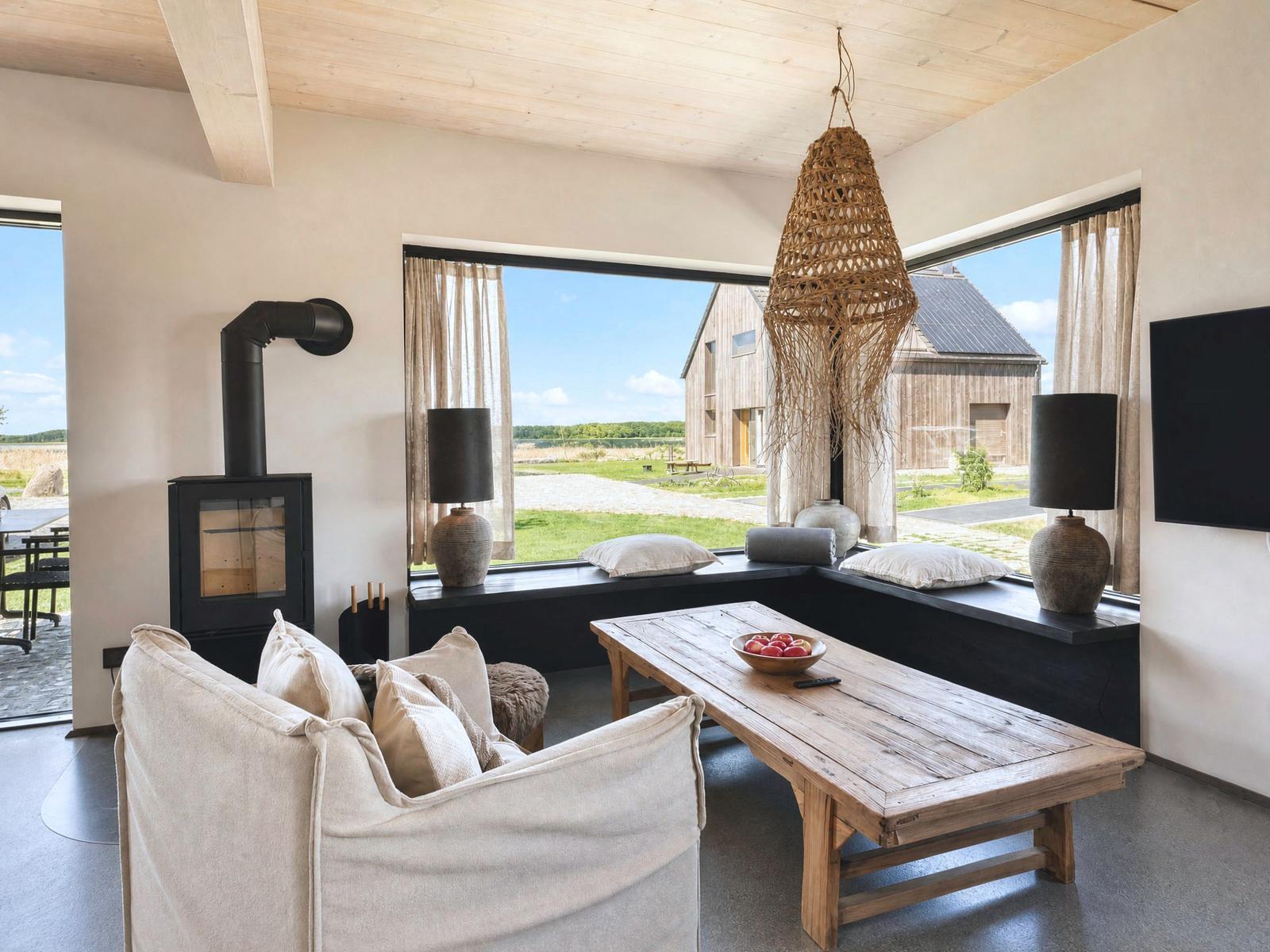 Living room with wooden ceiling, fireplace, and large window view of farm.
