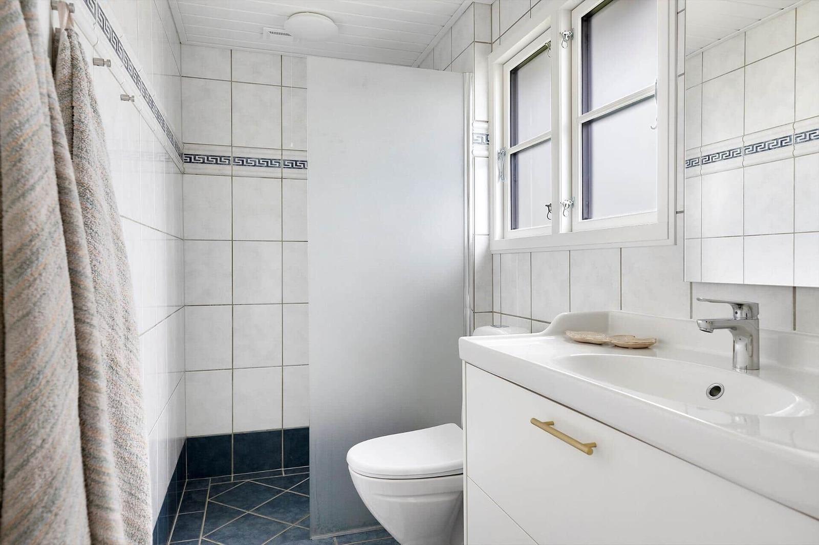 Bathroom with shower, toilet, and sink. Tiles with Greek pattern.