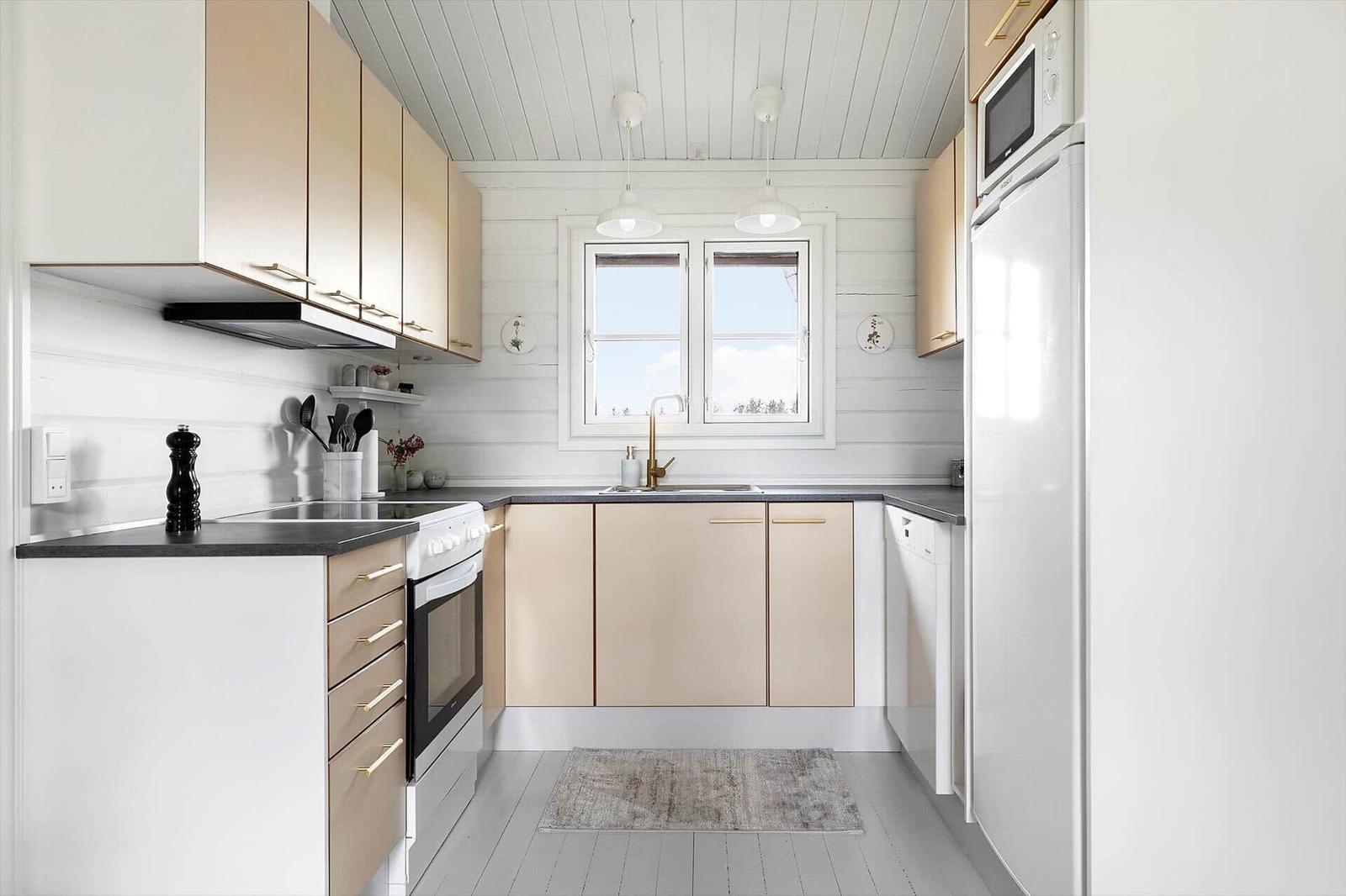 Kitchen with light cabinets, worktop and window. White walls and ceiling.