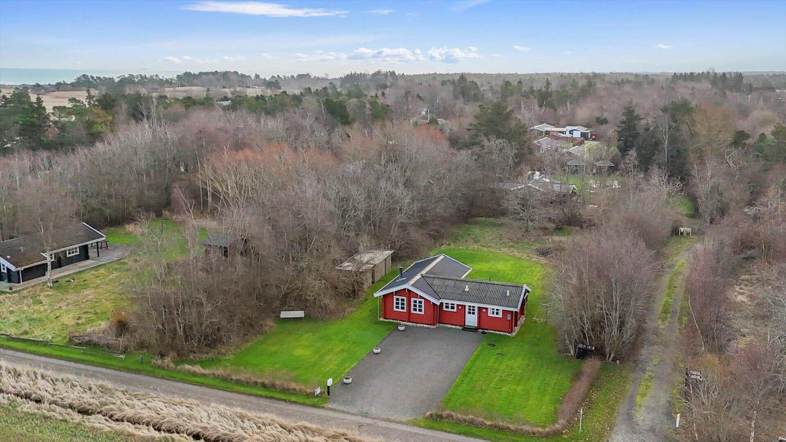 Red house with garage and lawn in the woods. View of the property.