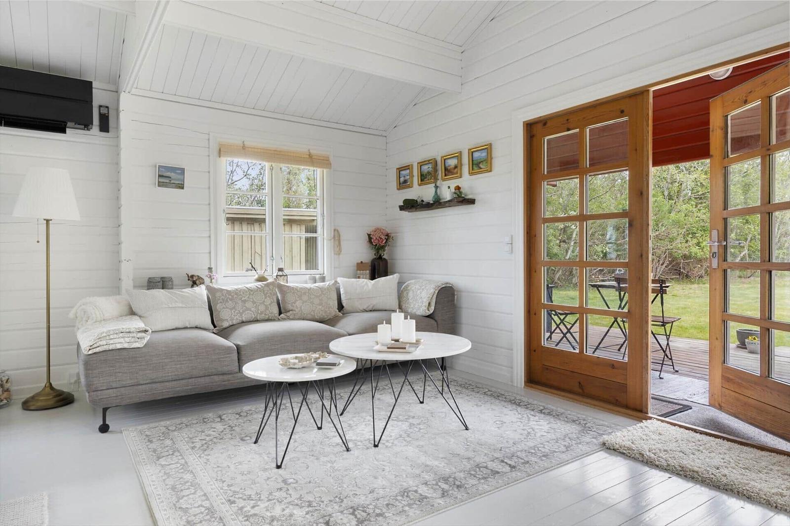 Living room with sofa, tables, and wooden door to terrace.