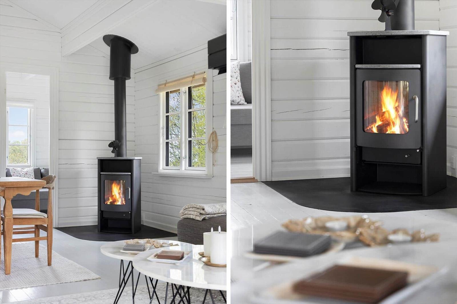 Black wood stove in white wooden house with window and seating area.