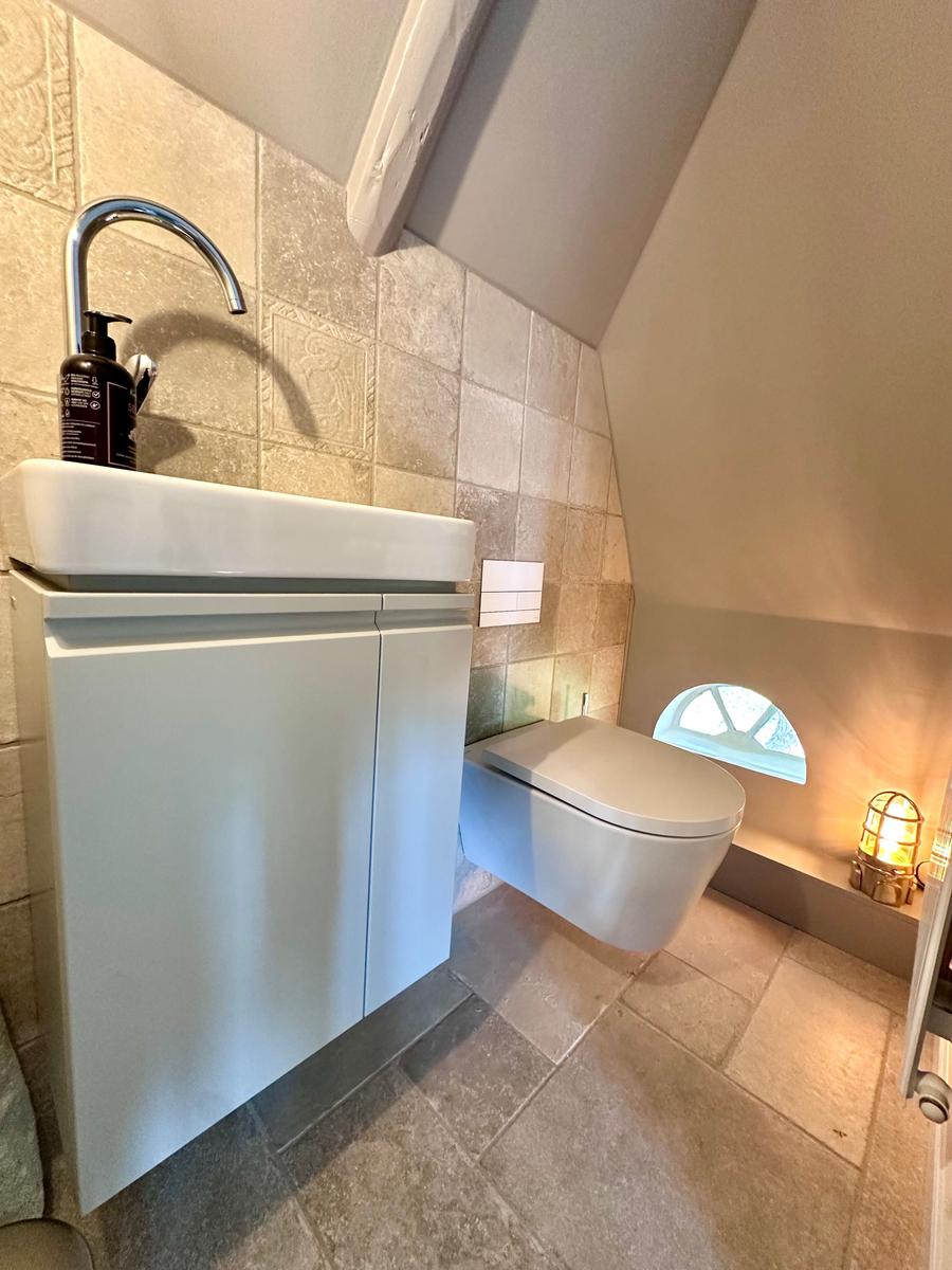 Badezimmer mit Waschbecken, WC und Fenster