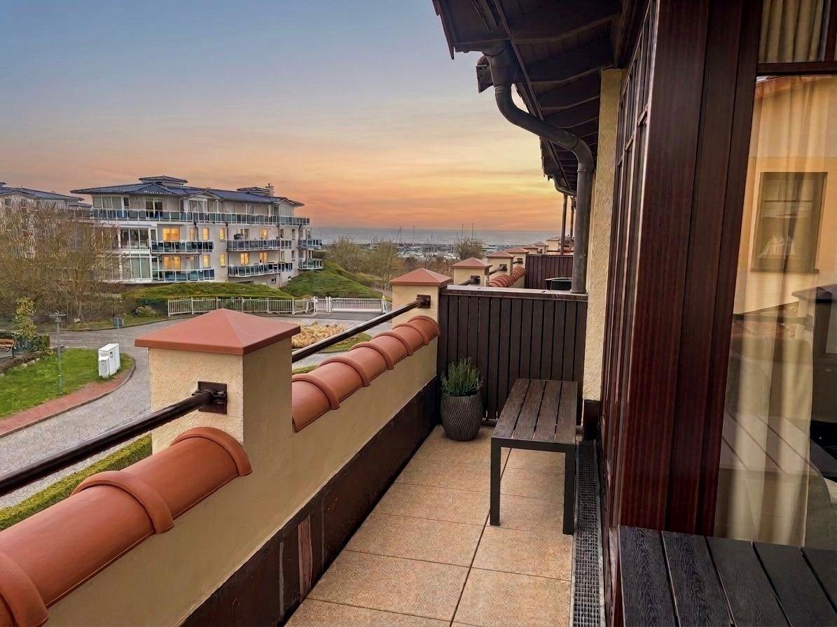Terrasse mit Blick auf See und Gebäude bei Sonnenuntergang.