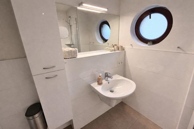 Badezimmer mit runden Fenster, Waschbecken und Spiegel