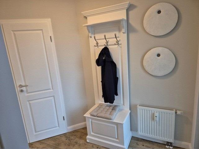 Haus-Eingang mit Kleiderständer, Wärmeregler und zwei runden Wanddekorationen.