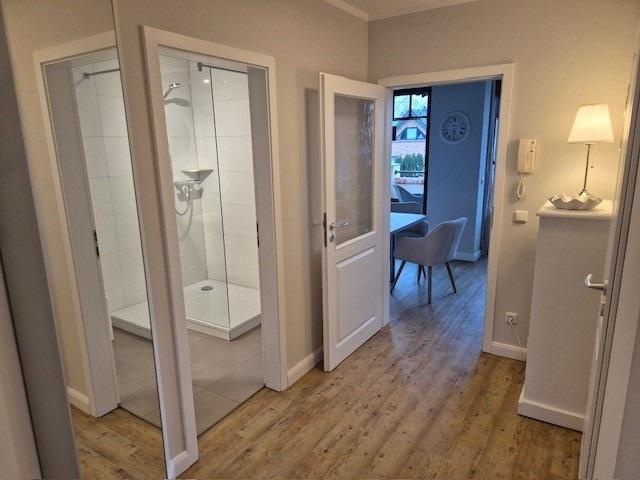 Flur mit Dusche, Schlafzimmer und Essbereich mit Stuhl und Tisch.