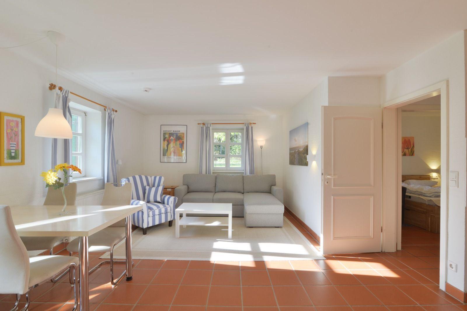 Wohn- und Essbereich mit Sofa, Stuhl und Tisch. Durchgang zur Schlafzimmer.