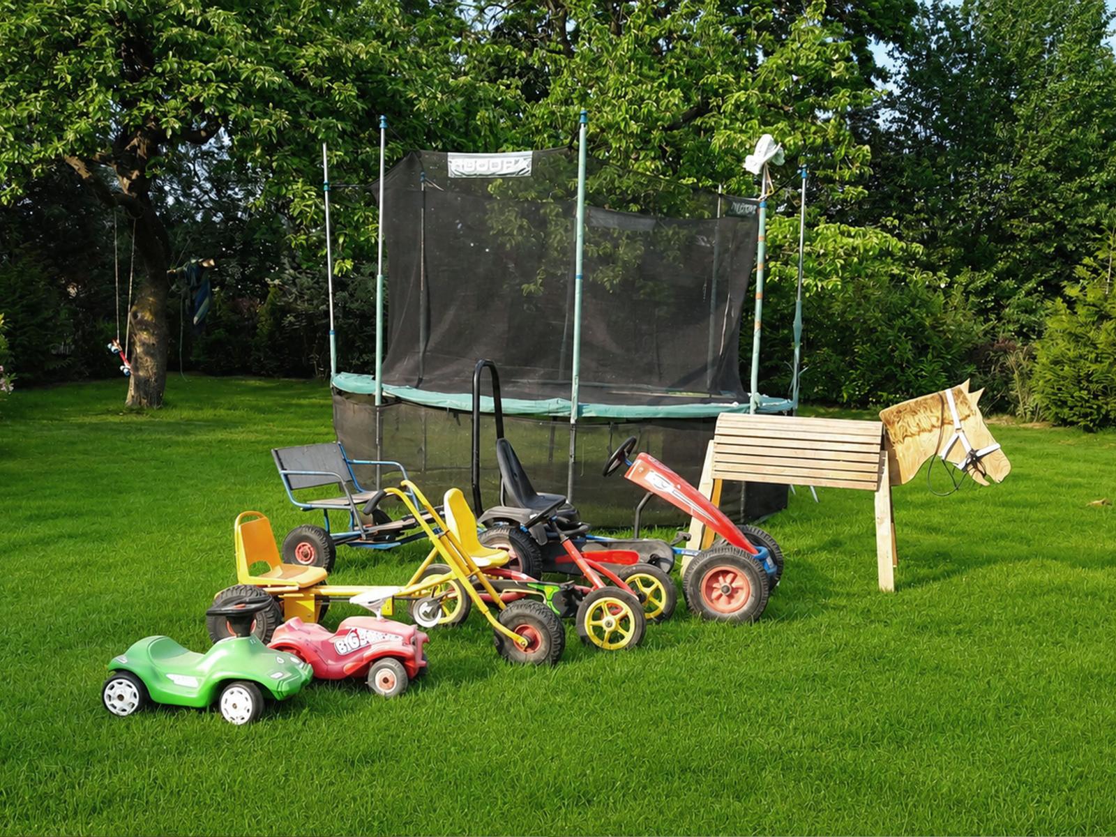 Garten mit Trampolin und Kinderspielzeug auf Rasenfläche.