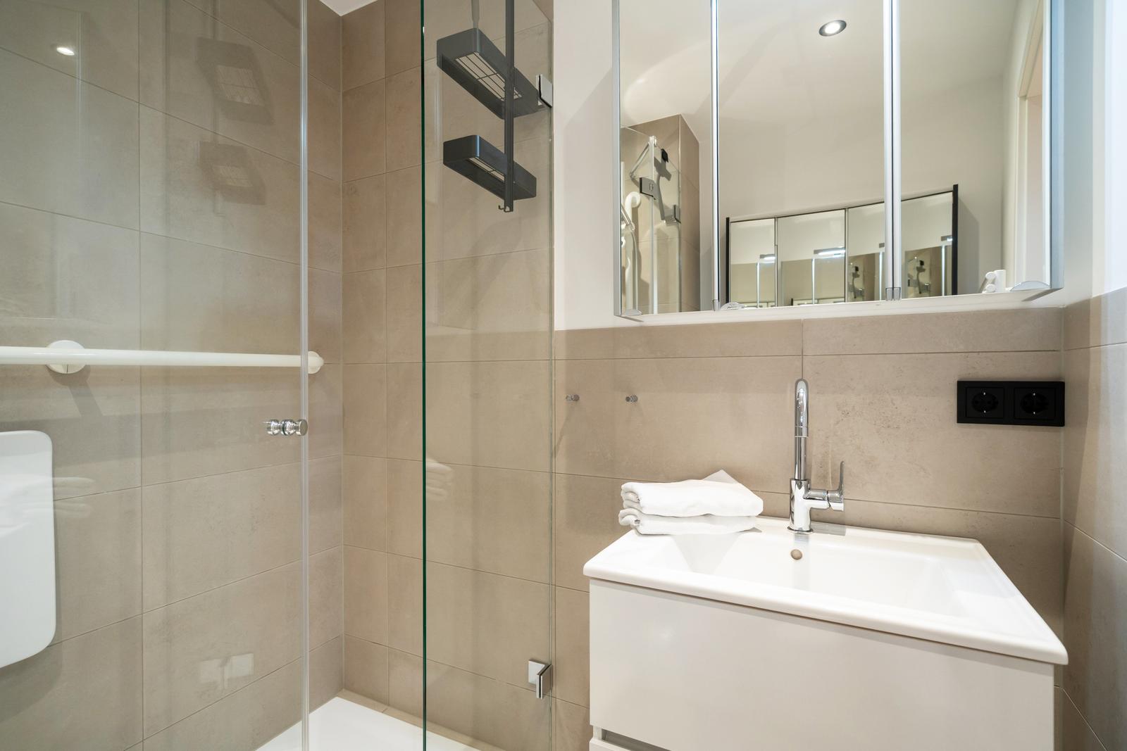 Dusche mit Glaswand, Waschbecken und Spiegel