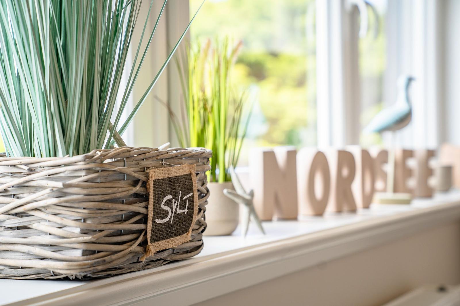 Fensterbrett mit Korb, Pflanzen und Holzbuchstaben NORDSEE.