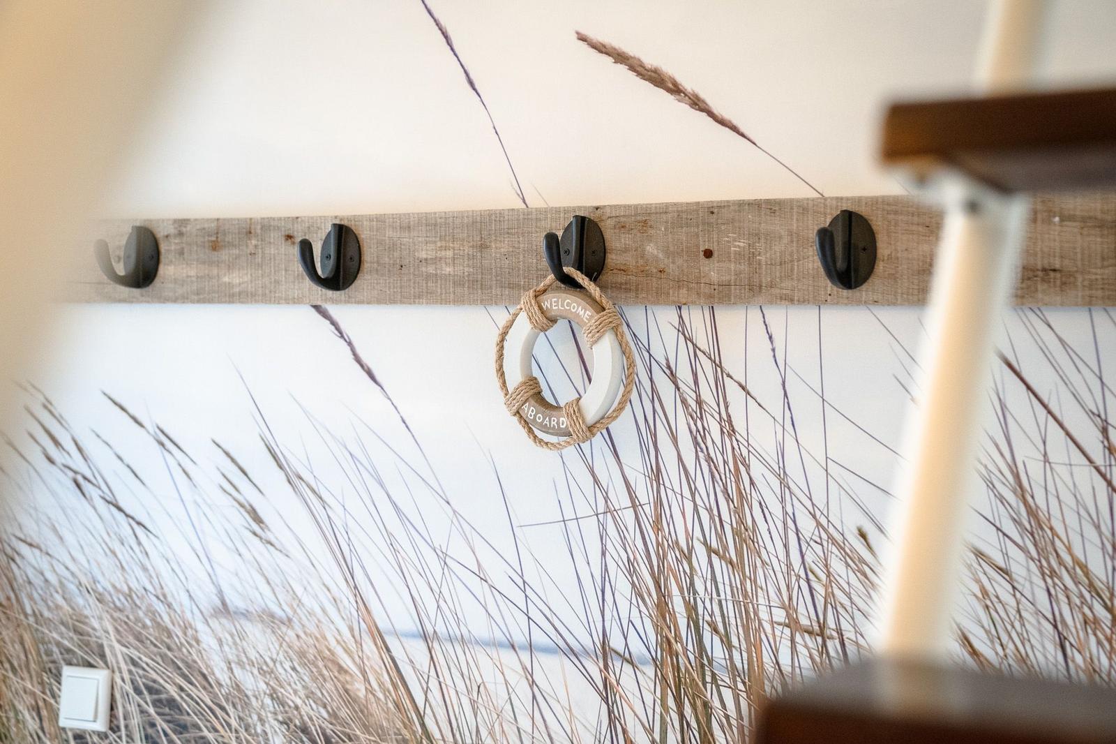 Holzstange mit Haken und Rettungsring an der Wand.