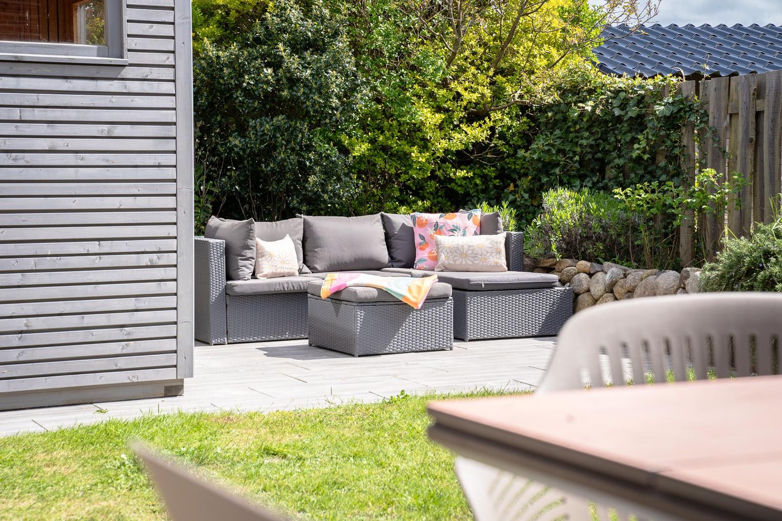 Garten mit grauem Sitzmöbelset und grüner Umgebung.