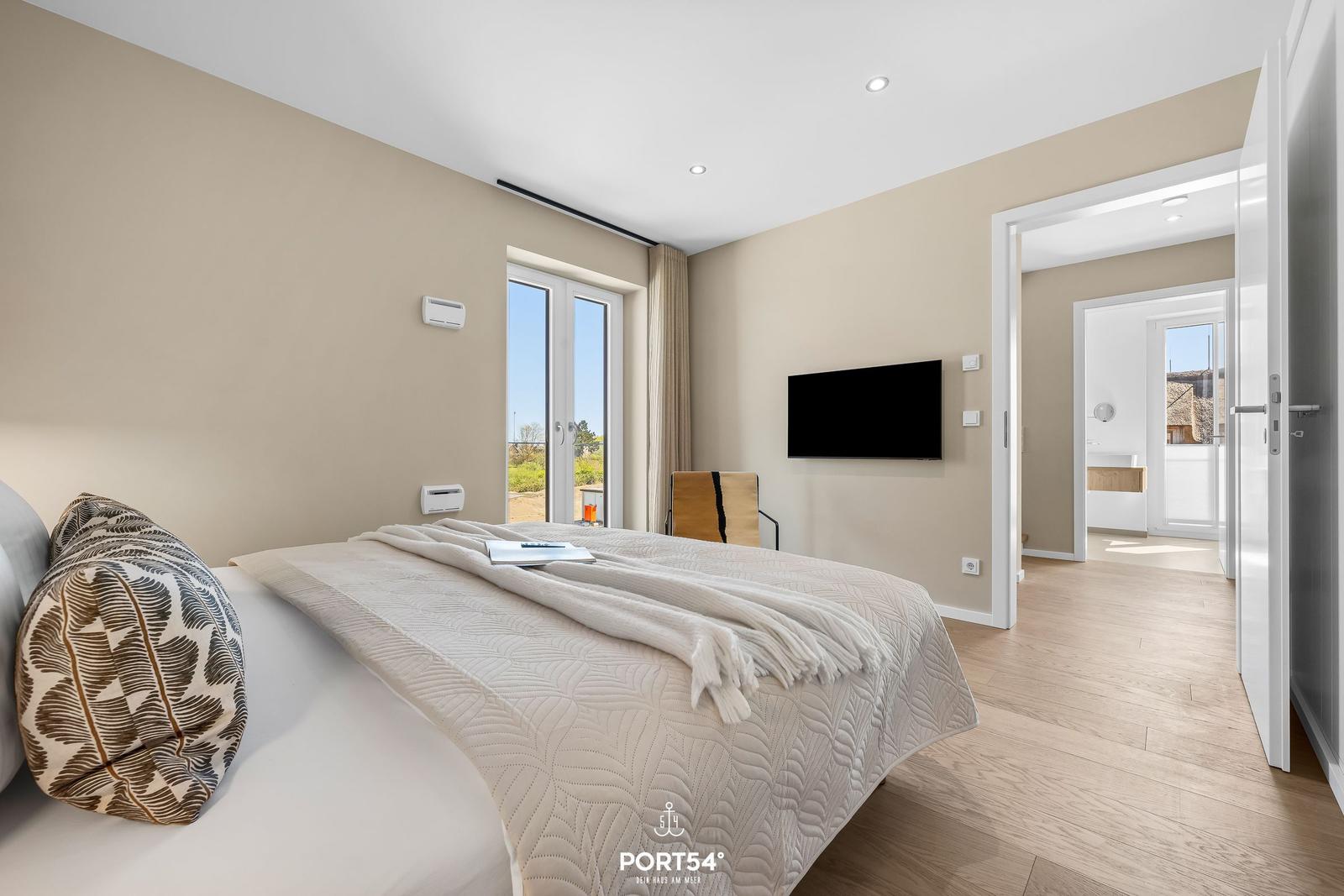 Bedroom with bed, TV, and view of outdoor area.