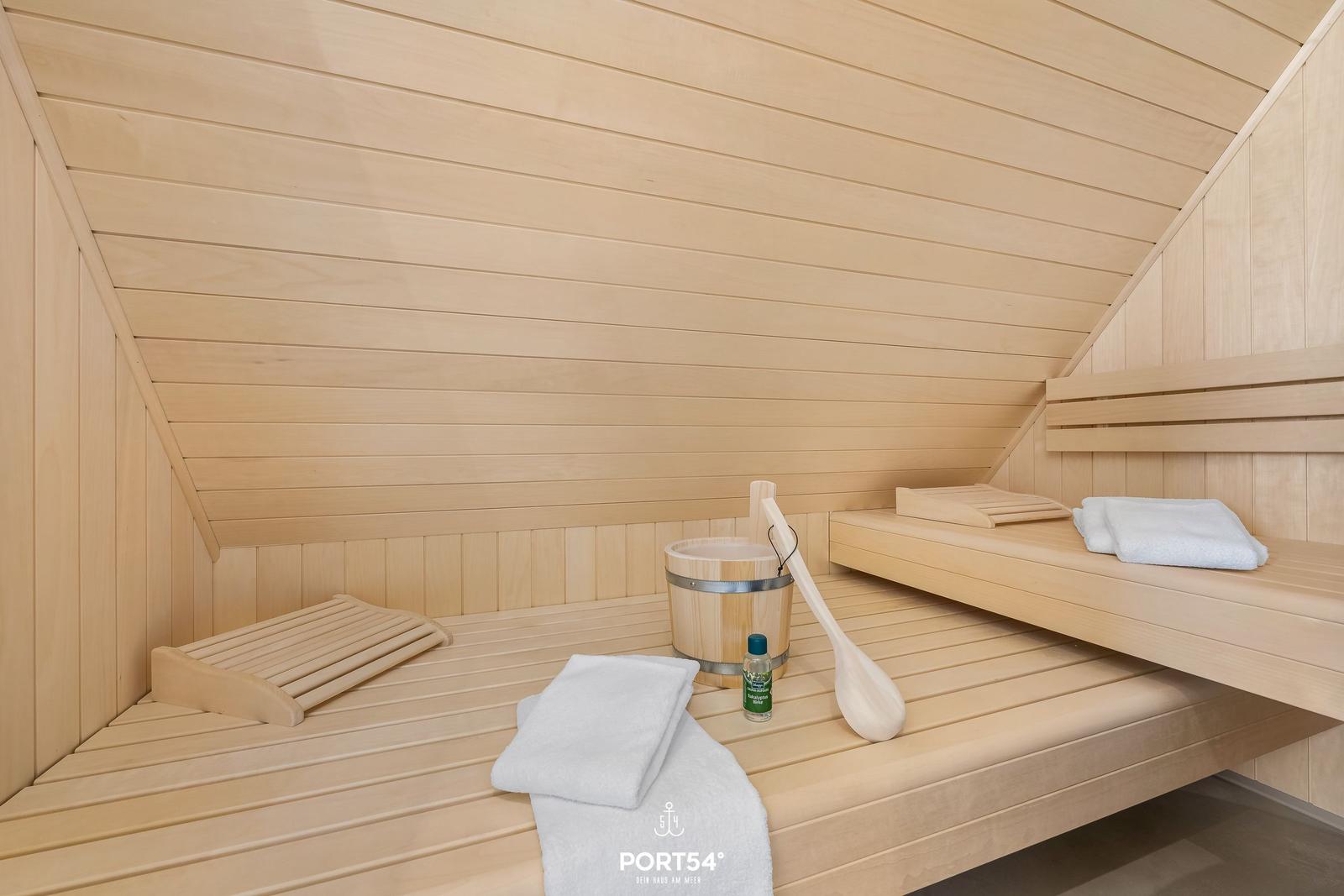 Sauna with wooden bench, bucket, shovel, and towels.