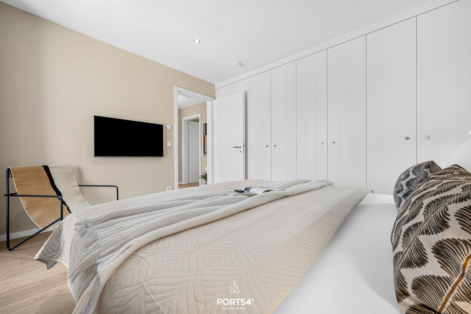 Bedroom with bed, wardrobe, and TV mounted on the wall.