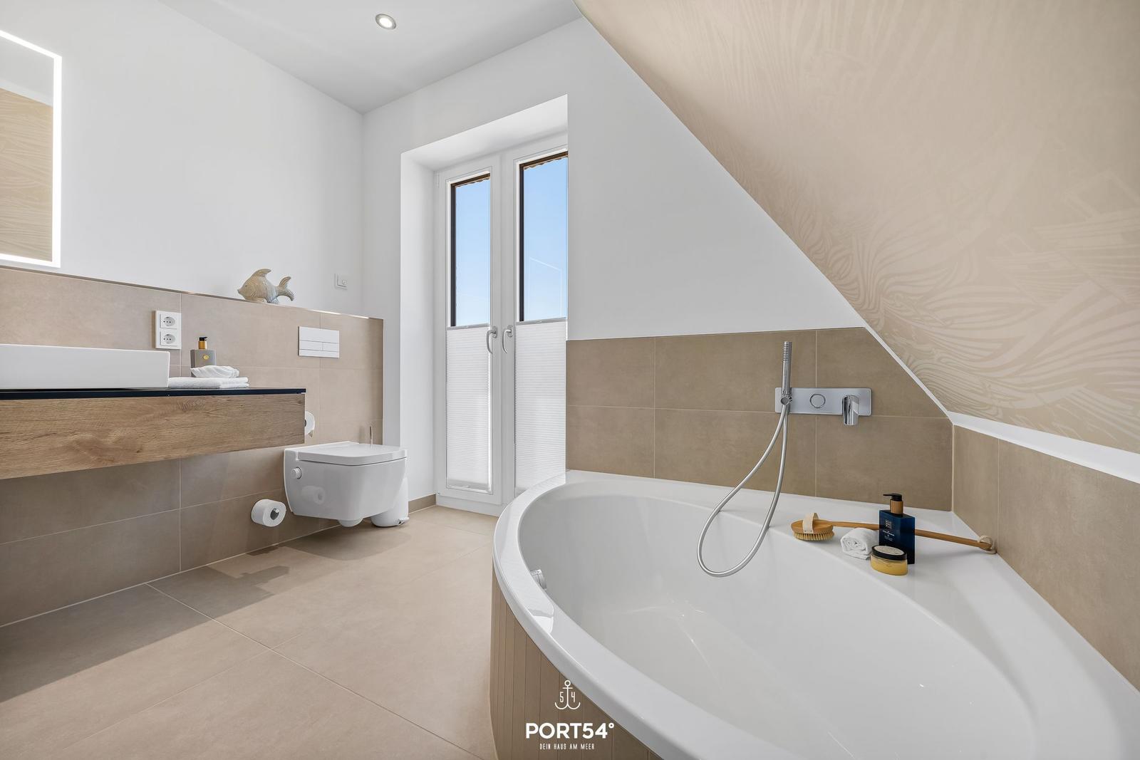 Bathroom with bathtub, sink, and toilet under a sloped ceiling.
