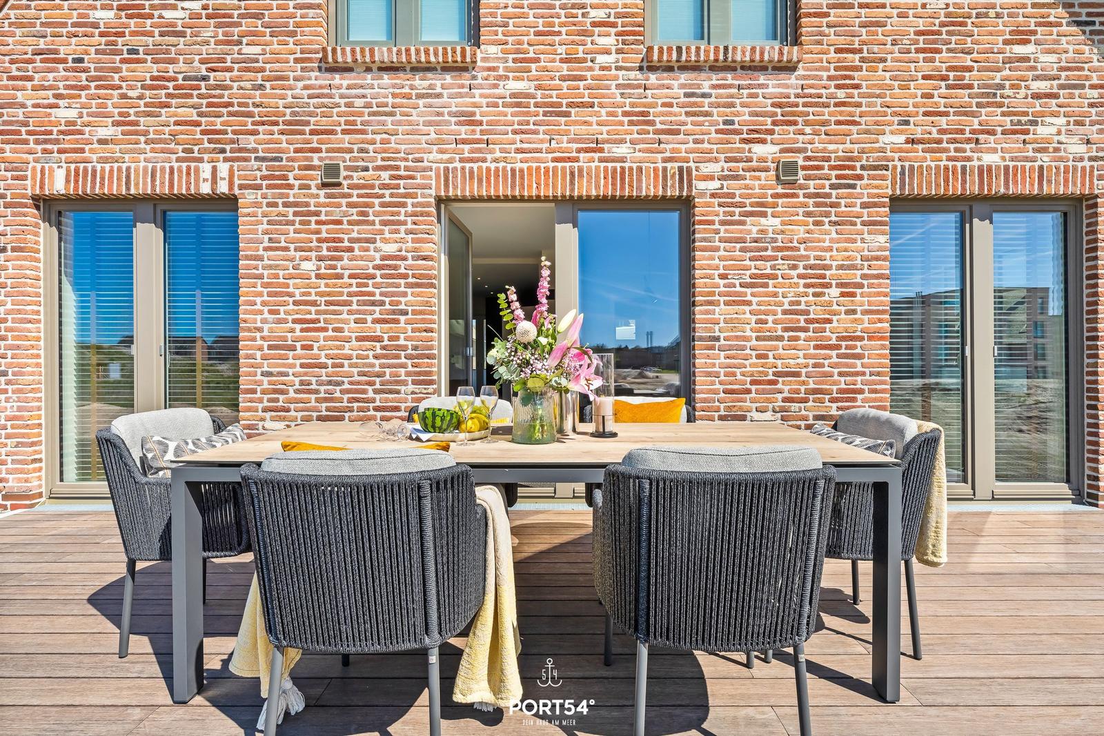 Terrace with table and chairs in front of brick house