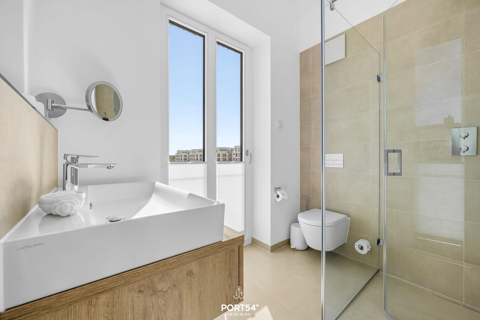 Bathroom with shower, toilet, and sink with window view.