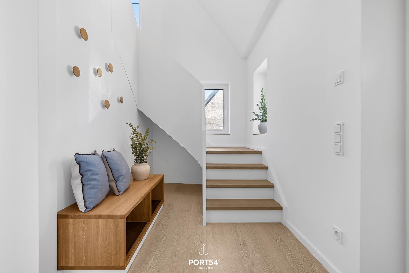 Staircase with wooden steps and bench under sloped ceiling