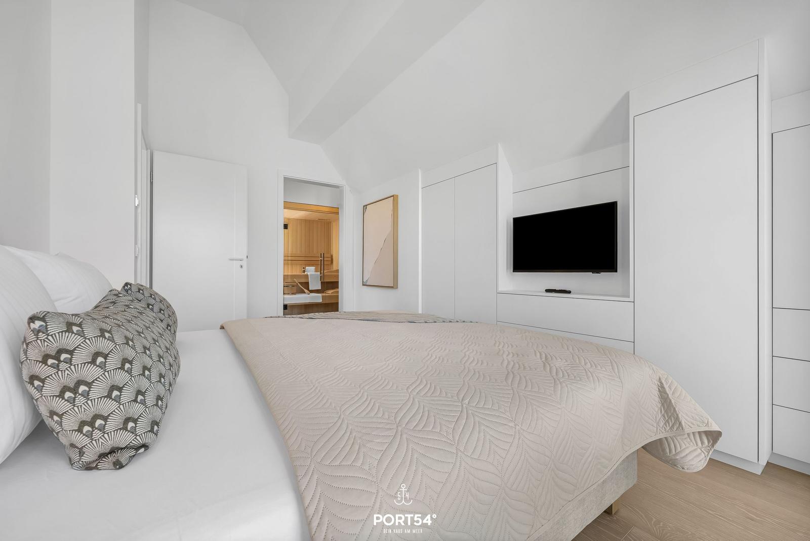 Bedroom with bed, TV, and view into the sauna.