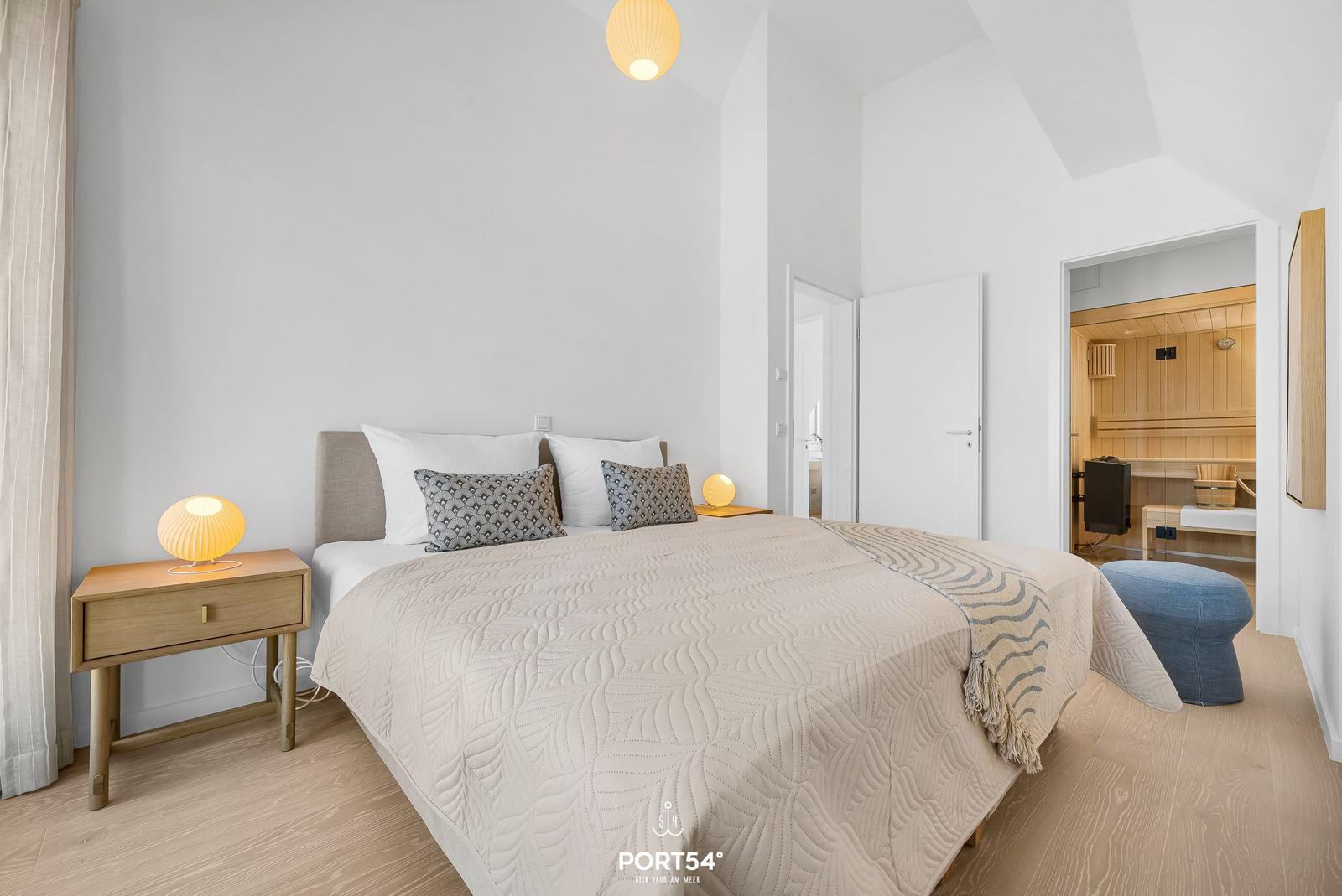 Bedroom with bed, nightstand, and sauna in the background.